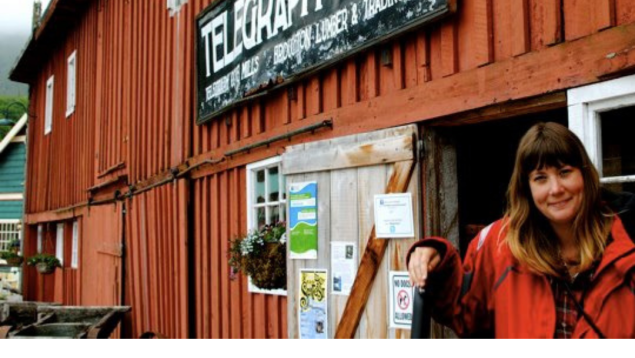 photo from telegraph cove with red building and Kate standing beside it