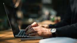 man with a watch outside on a laptop