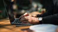 man with a watch outside on a laptop
